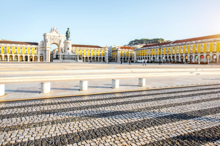Foto da Praça do Comércio com a estátua de D. José I e o Arco da Rua Augusta à esquerda e o castelo de S. Jorge à direita.